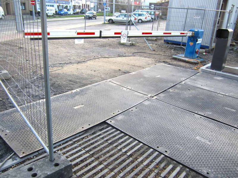 Mobile Baustraße aus Bodenschutzplatten, die eine sichere Zufahrt für Fahrzeuge und Maschinen über eine unbefestigte Fläche ermöglicht. Die Platten sind rutschfest und widerstandsfähig.