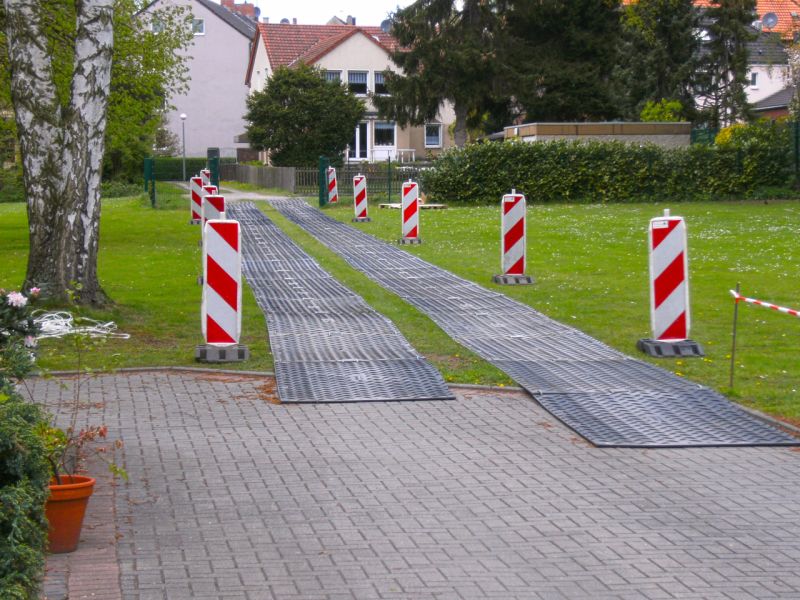 Fahrstreifen aus Platten führen über Wiesenbereich mit Leitbaken.
