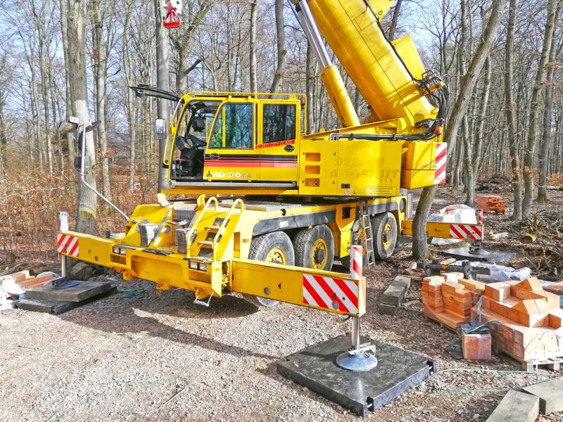 Mobiler Autokran mit ausgefahrenen Stützen auf Kranmatten aus Kunststoff im Waldgebiet