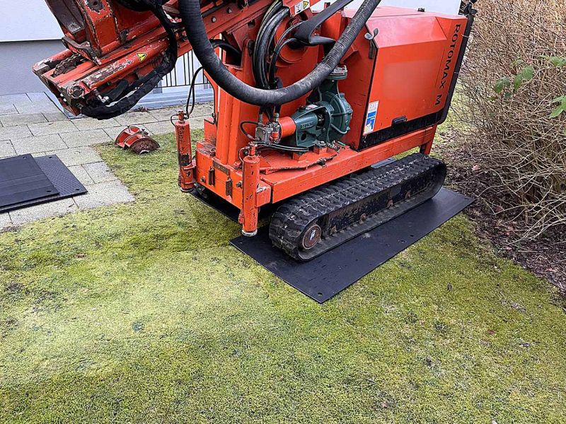 Eine Kleinbohrraupe steht auf Kunststoff-Fahrplatten zum Schutz des Rasens