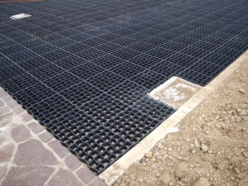 Bodengitter am Randstein montiert, sauberer Übergang zur Kiesfläche.