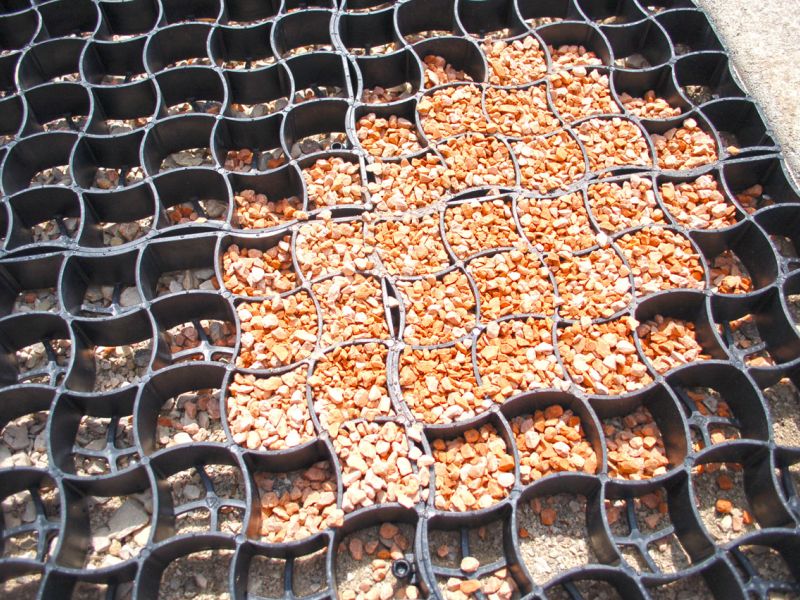 Nahaufnahme gefüllter Bodengitter mit rötlichem Kies.