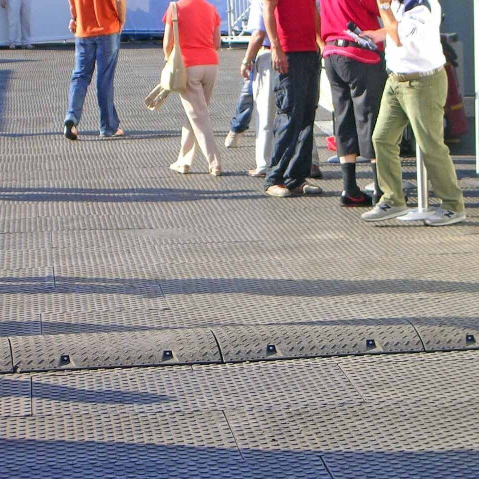 Fußgänger laufen über eine Fläche aus Bodenschutzmatten