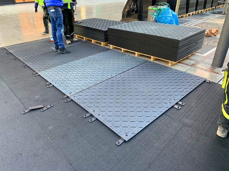 Zum Schutz des gepflasterten Untergrunds wurden x:tek46 Fahrplatten auf Gummimatte verlegt. Einige Platten liegen noch auf Paletten