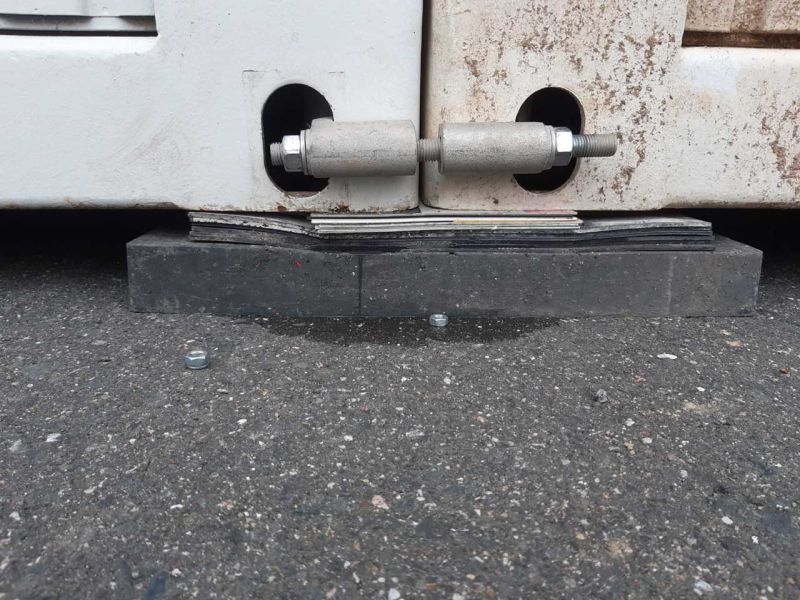 Nahaufnahme von Containerecken, die auf Nivellierplatten abgestützt sind.