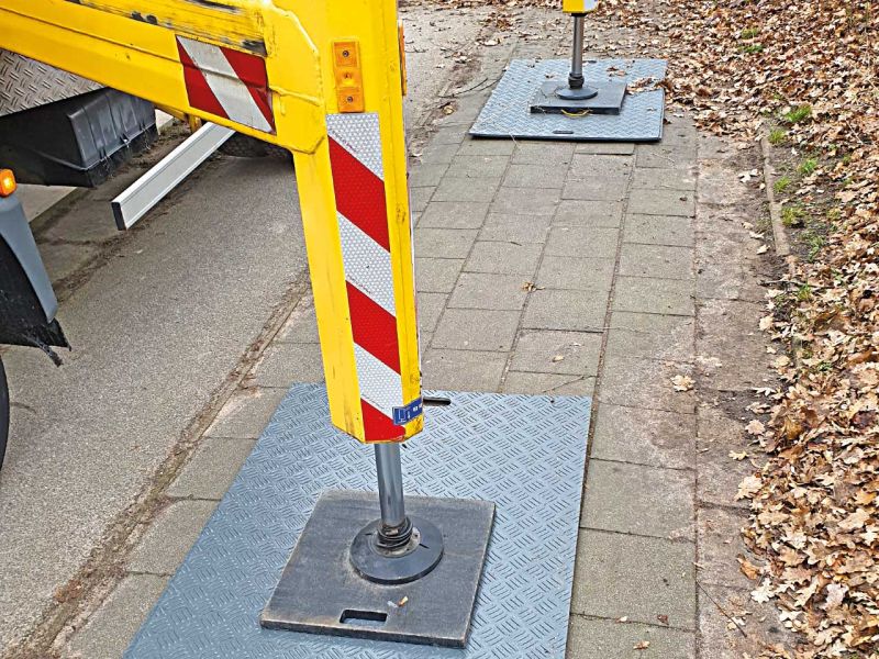 Mini-Fahrplatte aus Kunststoff unter der Stütze eines Kran-LKWs zur Stabilisierung.