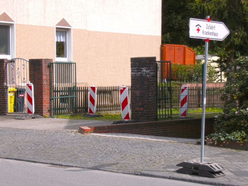 Temporäre Wegführung mit Klinikschild und Absperrbaken im Wohngebiet.
