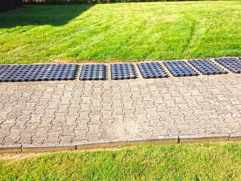 Kunststoff-Rasengitter auf Pflastersteinen ausgelegt. Einzelne Platten in Reihen für einen Parkplatz angeordnet.