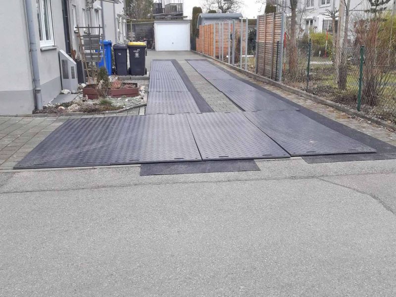 Baustelleneinrichtung mit e:tek PRO Fahrplatten und Gummimatten als Pflasterschutz in einer Hofeinfahrt