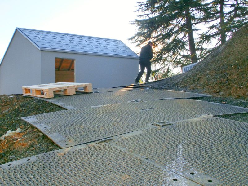 Mobile Baustraße aus Bodenschutzplatten in Hanglage, genutzt für den sicheren Zugang beim Bau eines Einfamilienhaus.