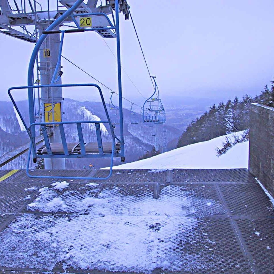 Winterliche Bergstation mit Sessellift und Schneeblick ins Tal. Bodenmatte wurden auf der Fläche vor dem Sessellift verlegt