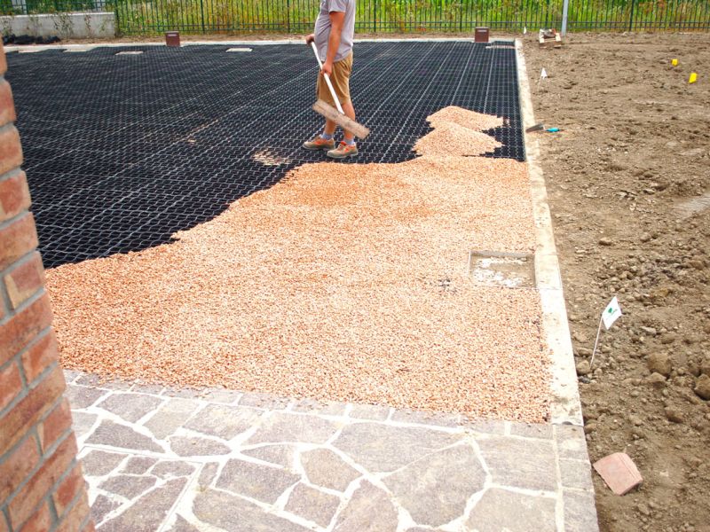 Handwerker verteilt Kies auf der Gitterfläche nahe dem Haus.