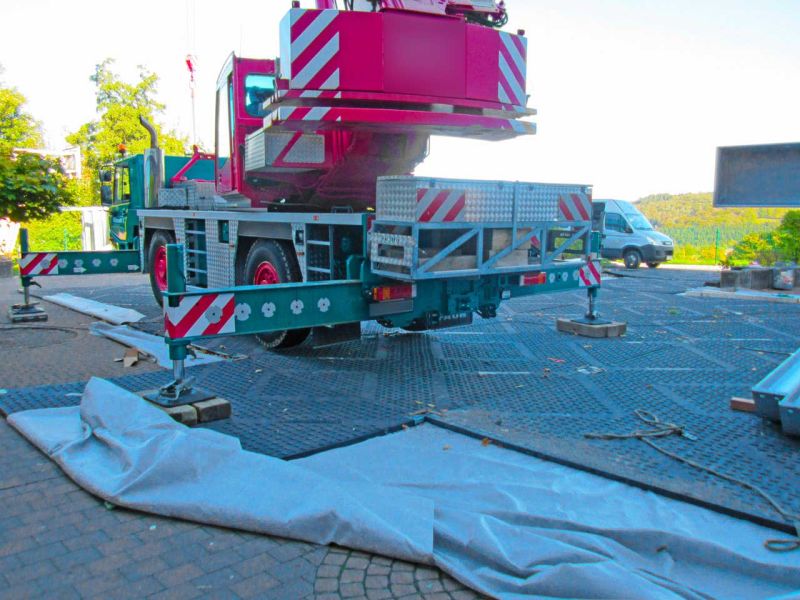 Mobilkran auf ausgelegten Kunststoffplatten mit stabilen Abstützungen, die den Pflasteruntergrund vor Druckschäden und Setzungen schützen.