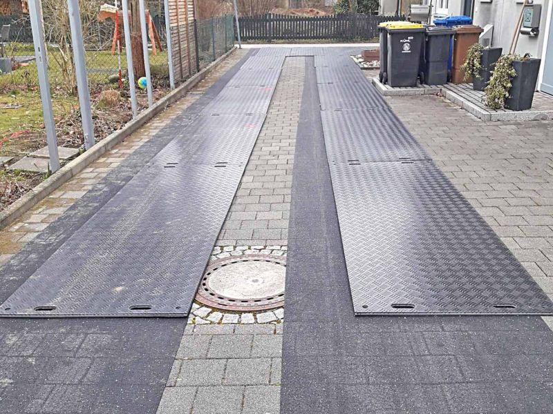 Baustelleneinrichtung mit e:tek PRO Fahrplatten und Gummimatten als Pflasterschutz in einer Hofeinfahrt