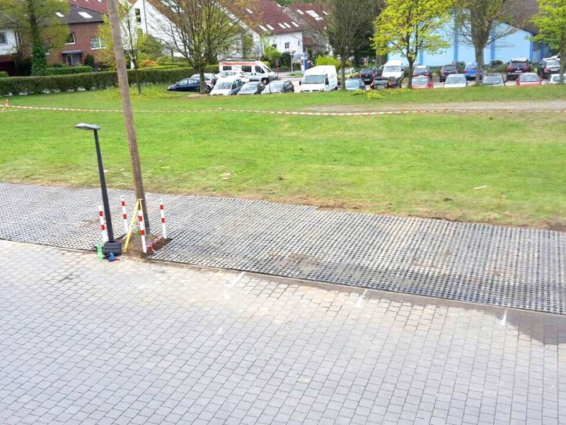 Aus einer erhöhten Position wurde eine Stellfläche aus Rasengittersteinen fotografiert, die auf einer Wiese neben einer Straße angelegt wurde.