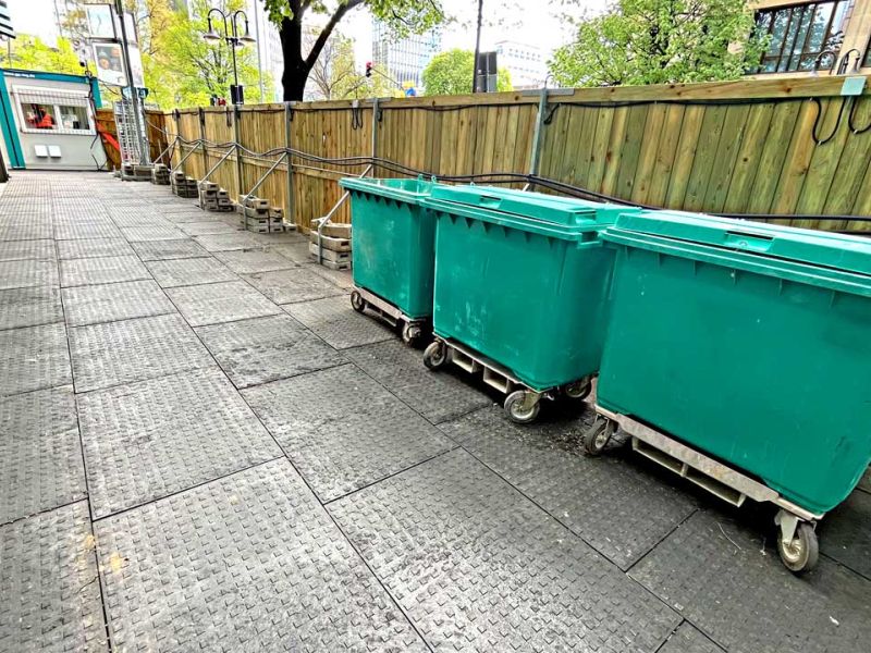 Drei Mülltonnen stehen auf Bodenmatten, die als Flächenschutz dienen