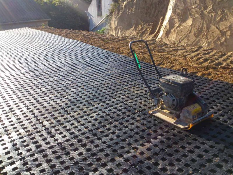 Eine Rüttelplatte steht auf einer Fläche aus Kunststoff Rasengittersteinen RGS35