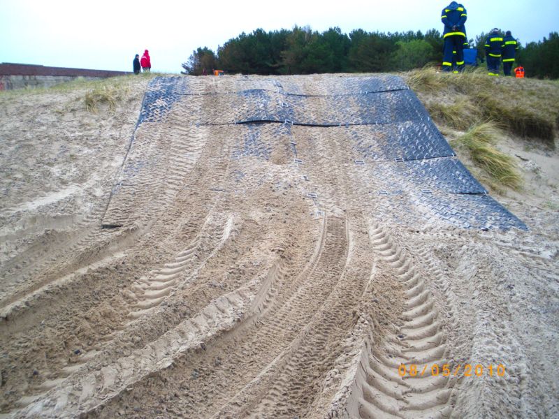 Ausgelegte Bodenschutzplatten stabilisieren eine sandige Steigung für Einsatzfahrzeuge.