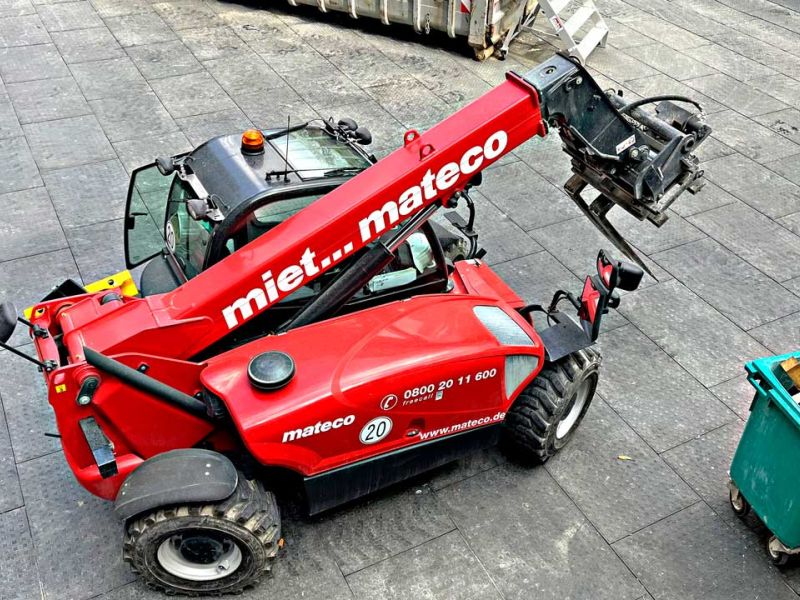 Ein roter Teleskoplader fährt über Bodenmatten, die auf einer Baustelle verlegt wurden