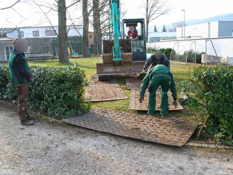 Mehrere Arbeiter verlegen s:tek-Bodenschutzplatten, um eine Fläche zu sichern.