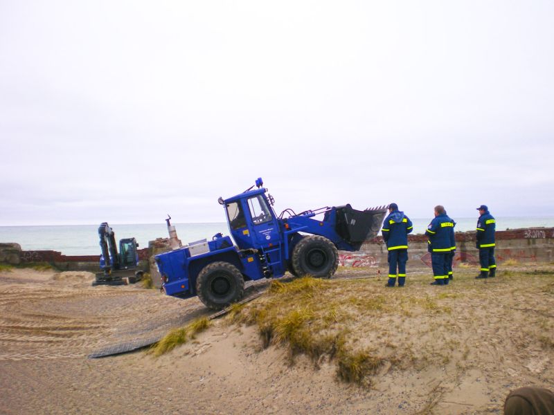Radlader überquert dank Bodenschutzplatten eine sandige Kuppe.