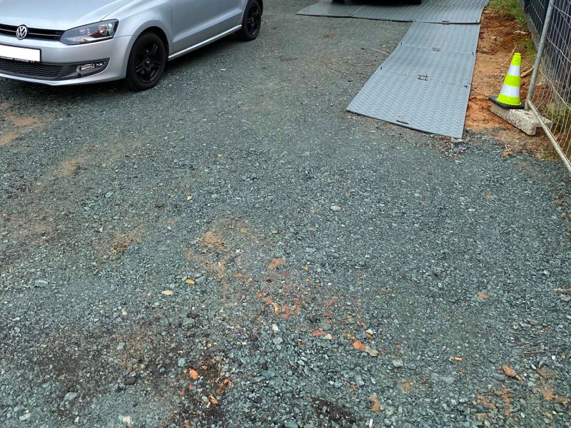 Unbefestigter Schotterboden mit sichtbaren Spurrillen und Mulden.