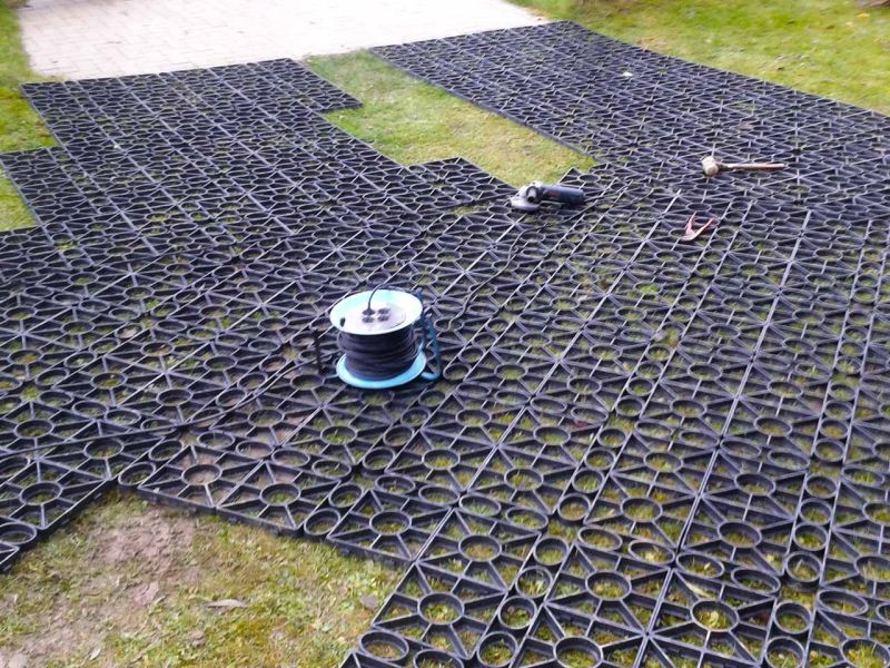 Rasengitter wurden auf einer Wiese verlegt. Darauf liegen verschiedene Werkzeuge.