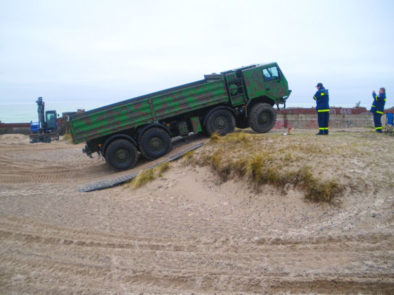 Militärfahrzeug fährt über sandige Hügel dank stabiler Platten.