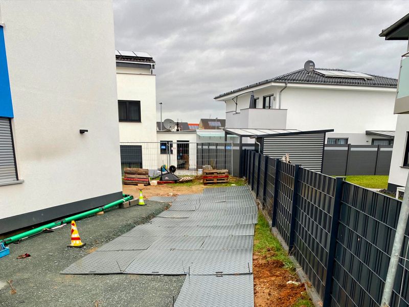 Kunststoffplatten bilden einen provisorischen, stabilen Zugangsweg im Wohngebiet.