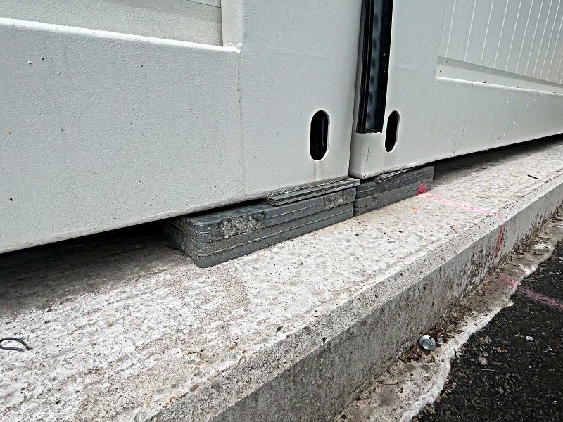 Zwei nebeneinaderstehende Container sind mit Unterlegplatten und dünnen Nivellierplatten so ausgerichtet, dass sie beide auf gleicher Höhe sind.