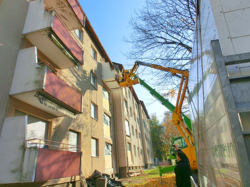Arbeitsbühne steht an der Fassade eines Mehrfamilienhauses für die Demontage eines Balkons, Zugang über vorbereitete Wege.