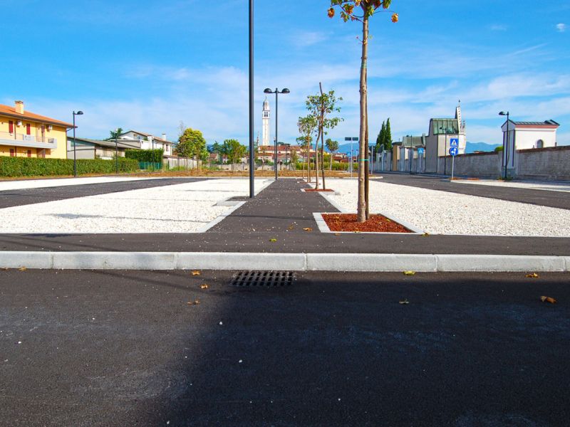 Gesamtansicht einer modernen Parkplatzanlage mit stabilisiertem Kies und Bäumen entlang der Fahrwege.