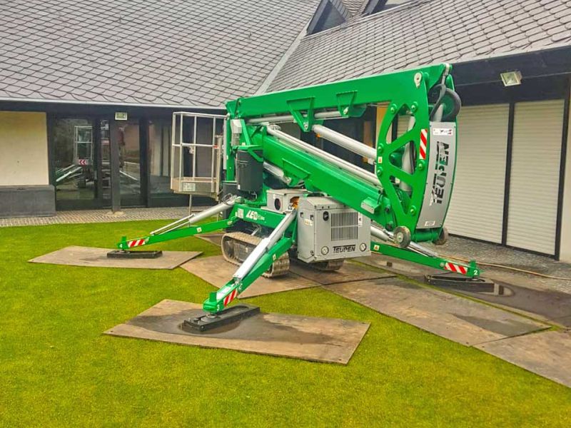Arbeitsbühne auf Rasen mit ausgelegten v:tek Fahrplatten als Unterlage