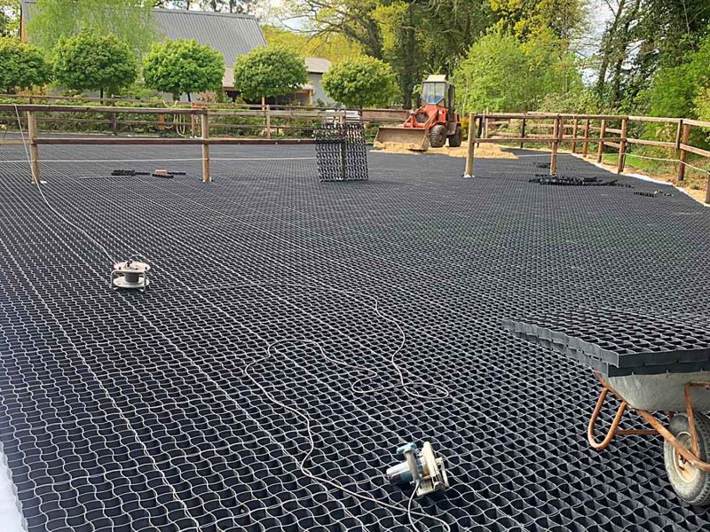 Ein Bagger verteilt Sand auf den verlegten Bodengittern