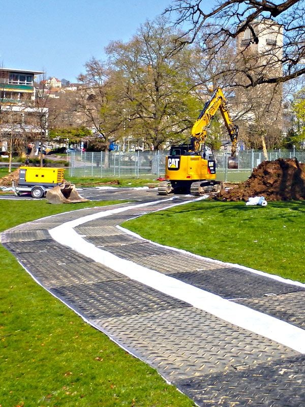 Auf einem Rasen verlegte Kunststoff-Bodenschutz-Systeme von Securatek über die ein Bagger fährt