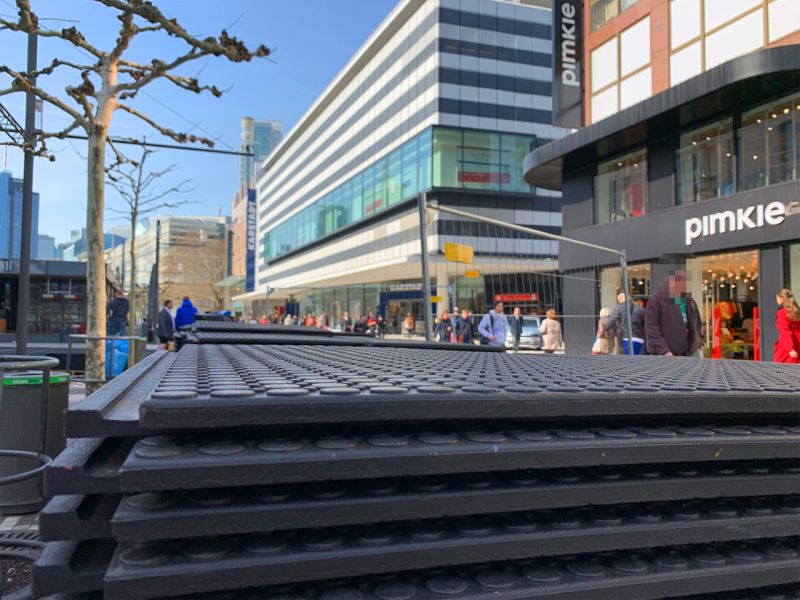 Nahaufnahme von gestapelten x:tek46 Fahrplatten. Man erkennt deutlich die Profilierung. Im Hintergrund sieht man hohe Gebäude und Schaufenster und viele Fußgänger.