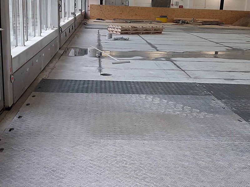 Ein Hallenboden aus Beton ist teilweise mit Fahrplatten aus Kunststoff abgedeckt