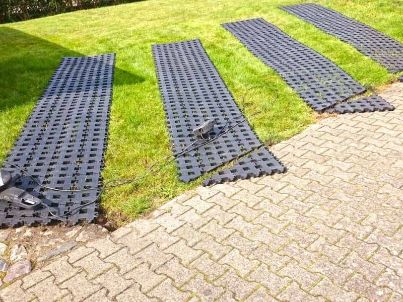 Kunststoff-Rasengitter mit einer Handkreissäge zugeschnitten. Kabelrolle liegt auf dem Rasen.