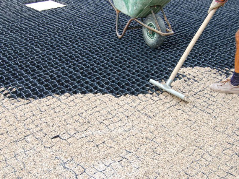 Kies wird in die Gitterstruktur gefüllt und gleichmäßig verteilt.