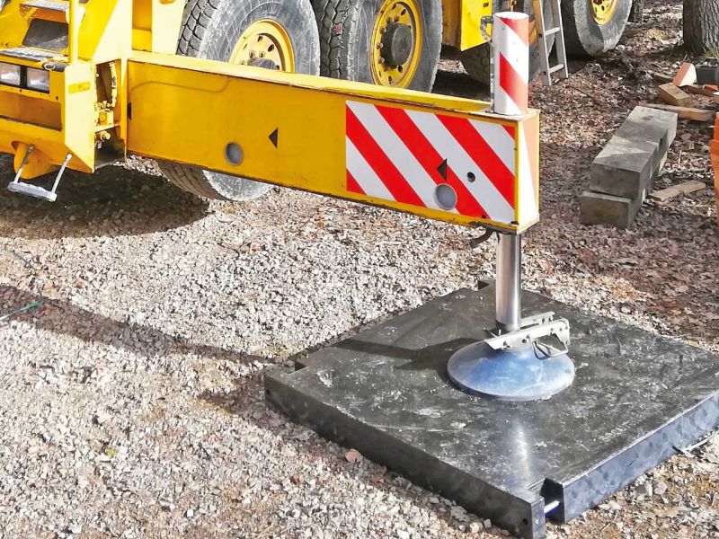 Abgestützte Kranstütze auf rechteckiger Kranmatte aus Kunststoff auf Schotterboden