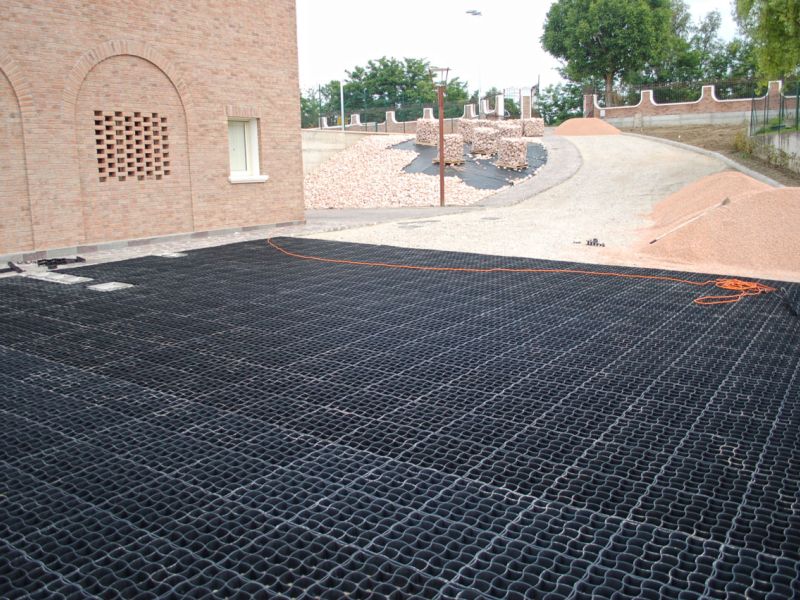 Ausgelegte Bodengitter vor einem mediterranen Haus als Unterbau der Kiesfläche.