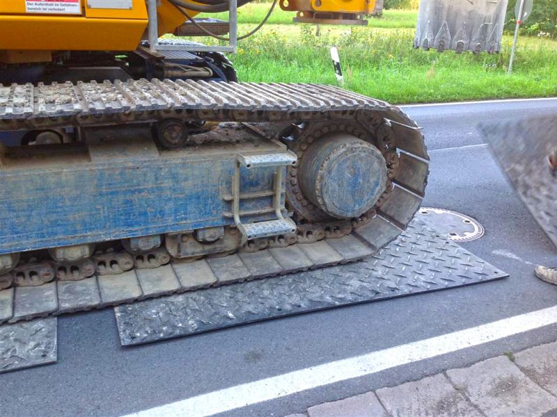 Stahlketten des Bohrgeräts auf robusten Schutzplatten zum Asphaltschutz.