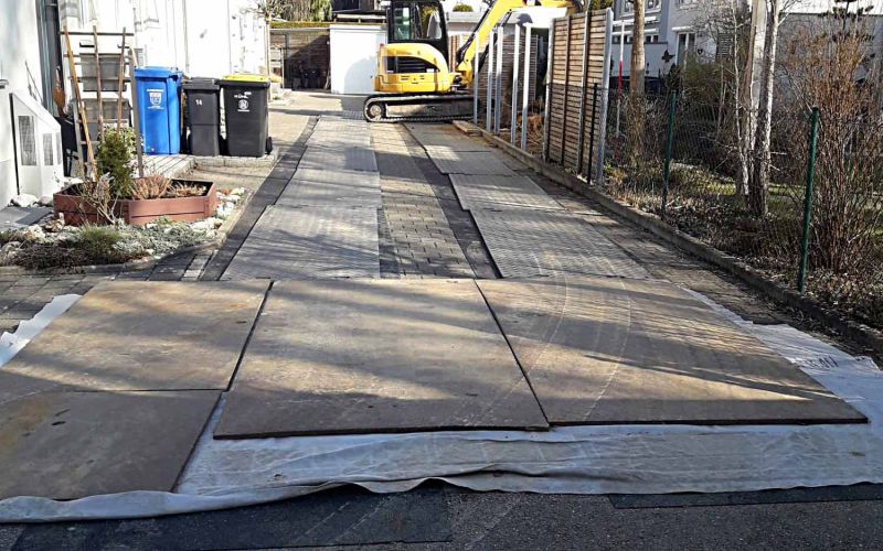 Baustelleneinrichtung mit e:tek PRO Fahrplatten und Gummimatten als Pflasterschutz in einer Hofeinfahrt