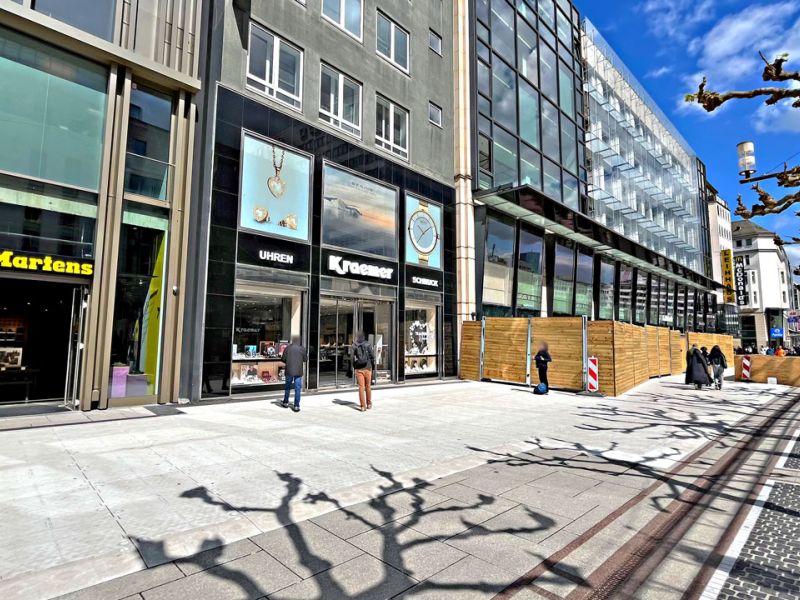 Bodenschutzmatten bei einer Baustelle in einer Fußgängerzone vor den Ladenfronten von Geschäften.