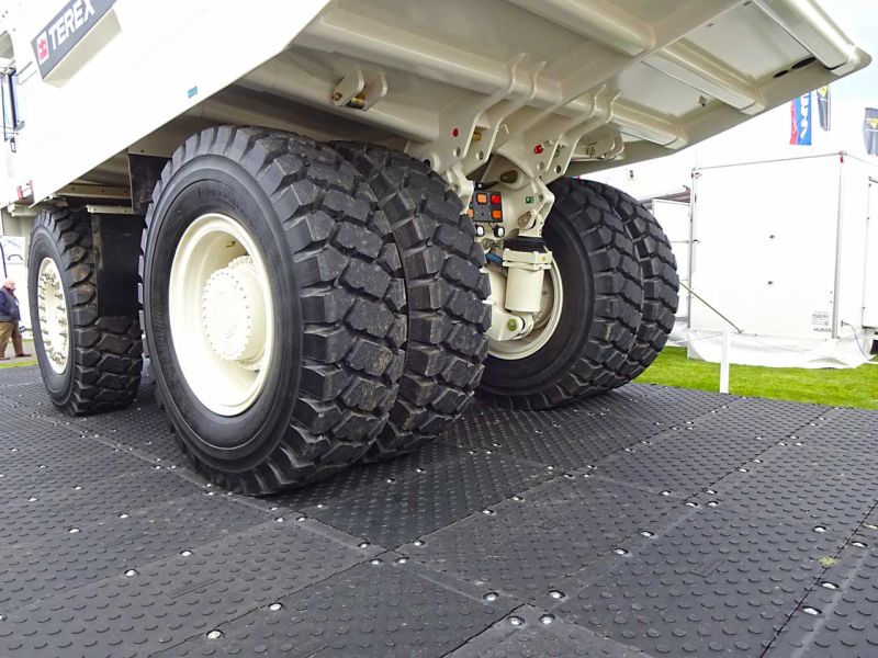 Ein weißer Muldenkipper fährt über eine mobile Baustraße aus Kunststoff-Schwerlast-Fahrplatten