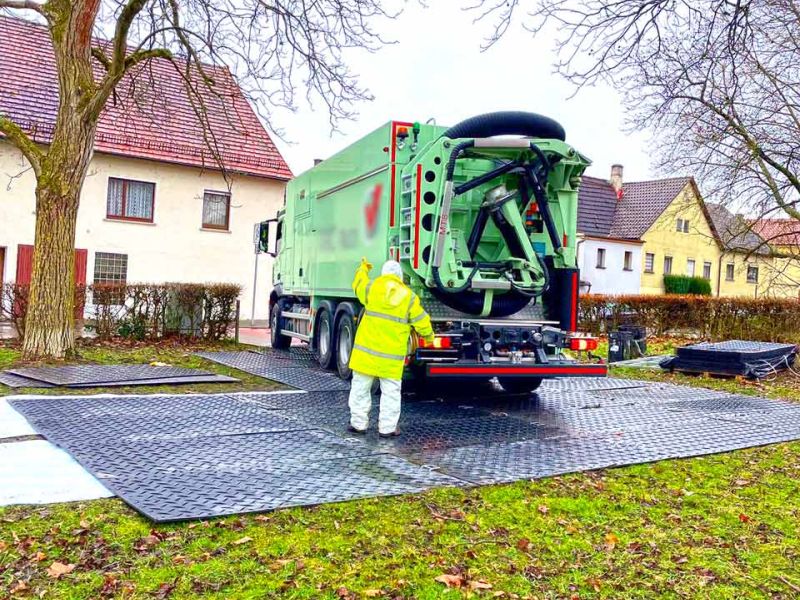 Ein Saugbagger auf Kunststoff-Bodenschutzplatten verhindert Bodenverdichtung und schützt Baumwurzeln beim Bau von Ersatz-Parkplatz in Heilbronn-Horkheim.