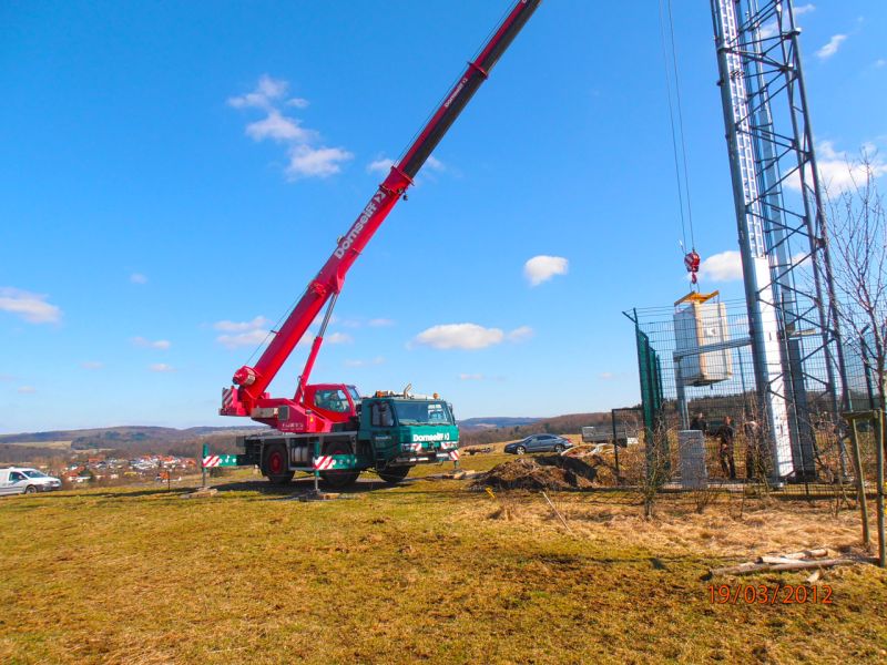 Teleskopkran transportiert Modul über Bodenschutzplatten bei Mobilfunkmast-Montage
