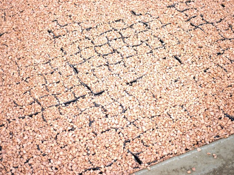 Fläche mit teils gefüllten Gitterwaben und rötlichem Kies.