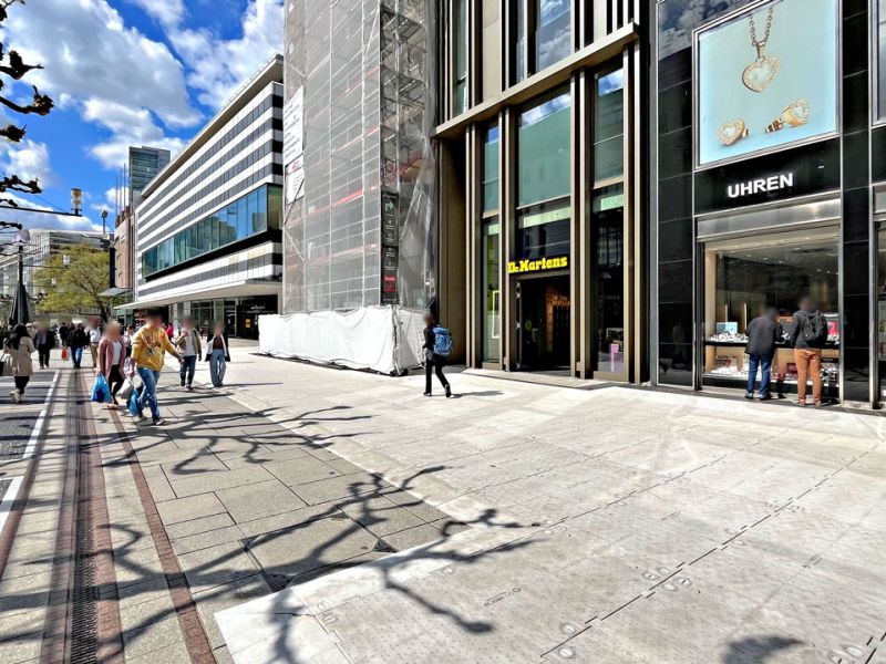 Auf einem gepflasterten Boden liegen Bodenschutzplatten. Man sieht den Eingang eines Geschäfts.