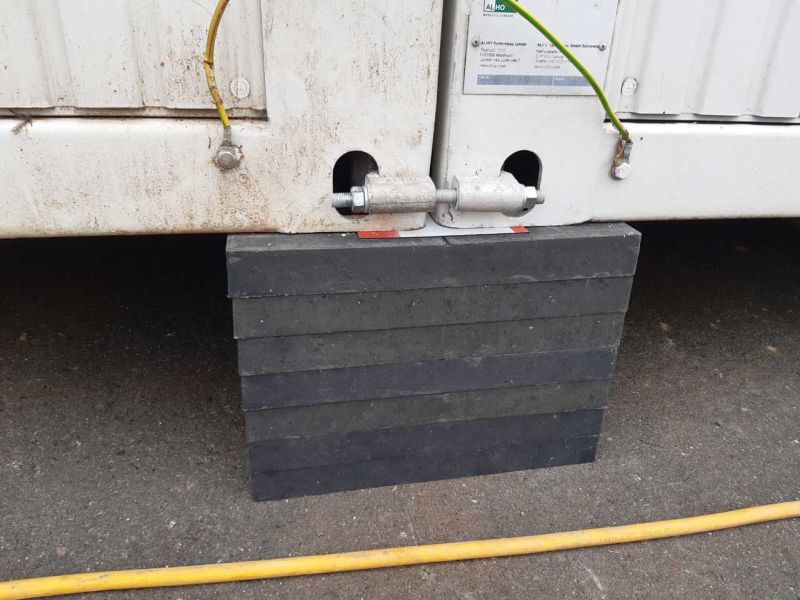 Gestapelte Unterlegplatten unter Containern zum Niveauausgleich und zur Unterpallung